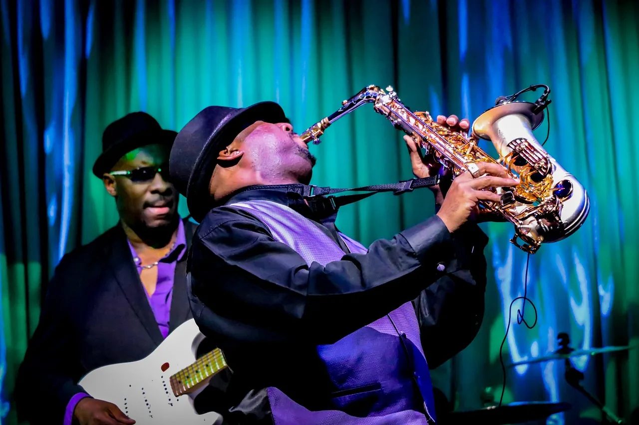 Saxophoniste et guitariste sur une scène éclairée
