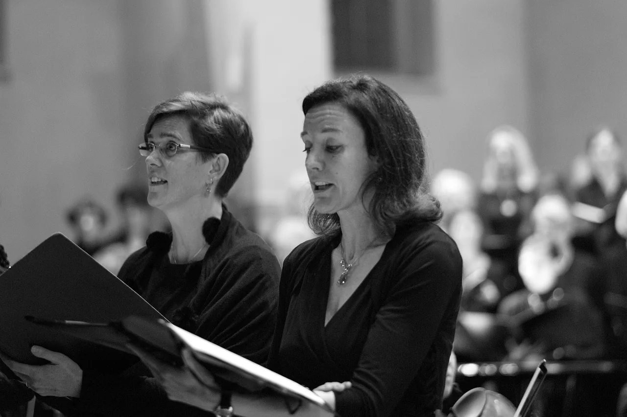 Deux choristes chantant avec leurs partitions