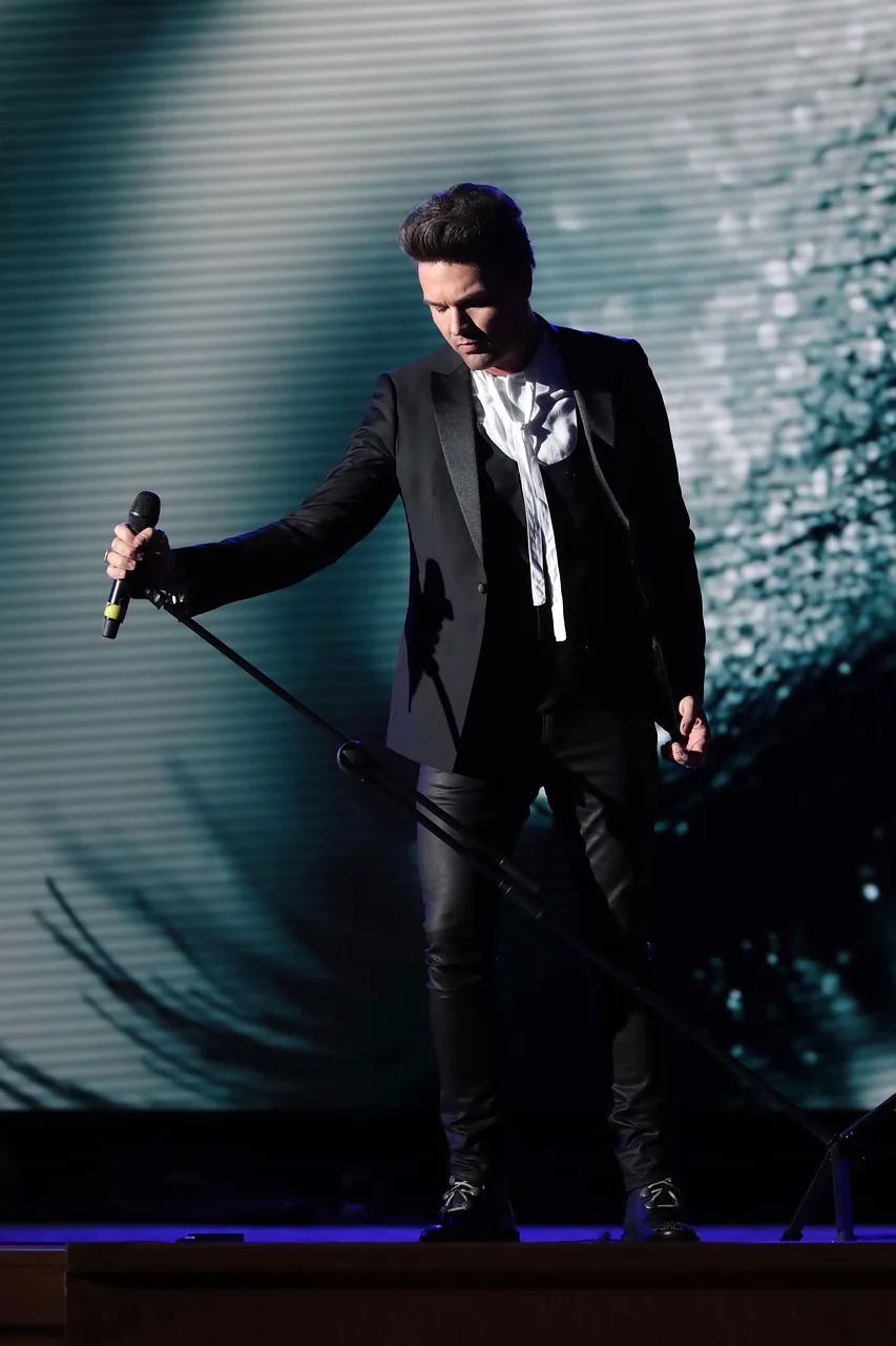 Singer in a black suit on stage Singer in a black suit on stage
