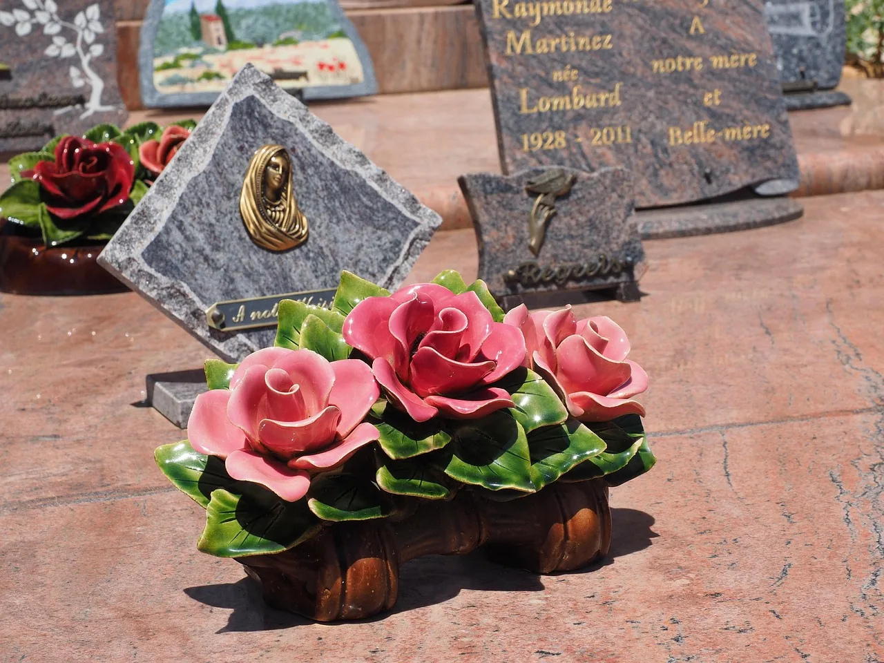 Roses en céramique et plaques sur une tombe Roses en céramique et plaques sur une tombe