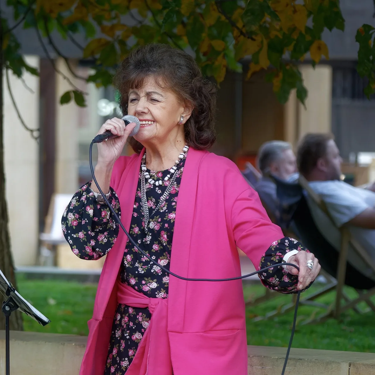 Singer in a pink outfit performing outdoors Singer in a pink outfit performing outdoors