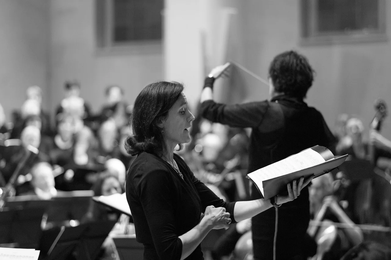 Singer with sheet music in front of an orchestra Singer with sheet music in front of an orchestra