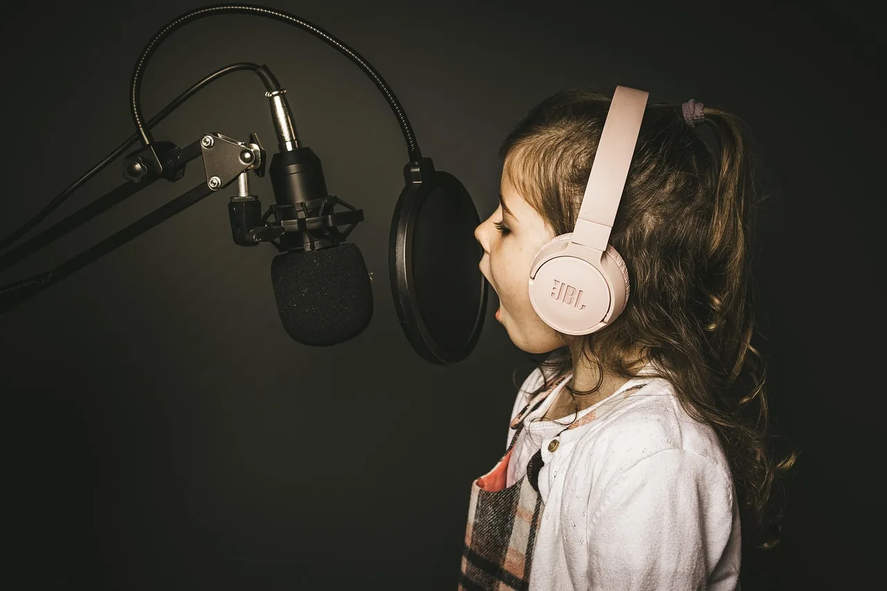 Child singing into a microphone with pink headphones Child singing into a microphone with pink headphones