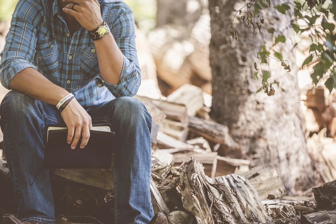 Person sitting and holding a book in a forest Person sitting and holding a book in a forest