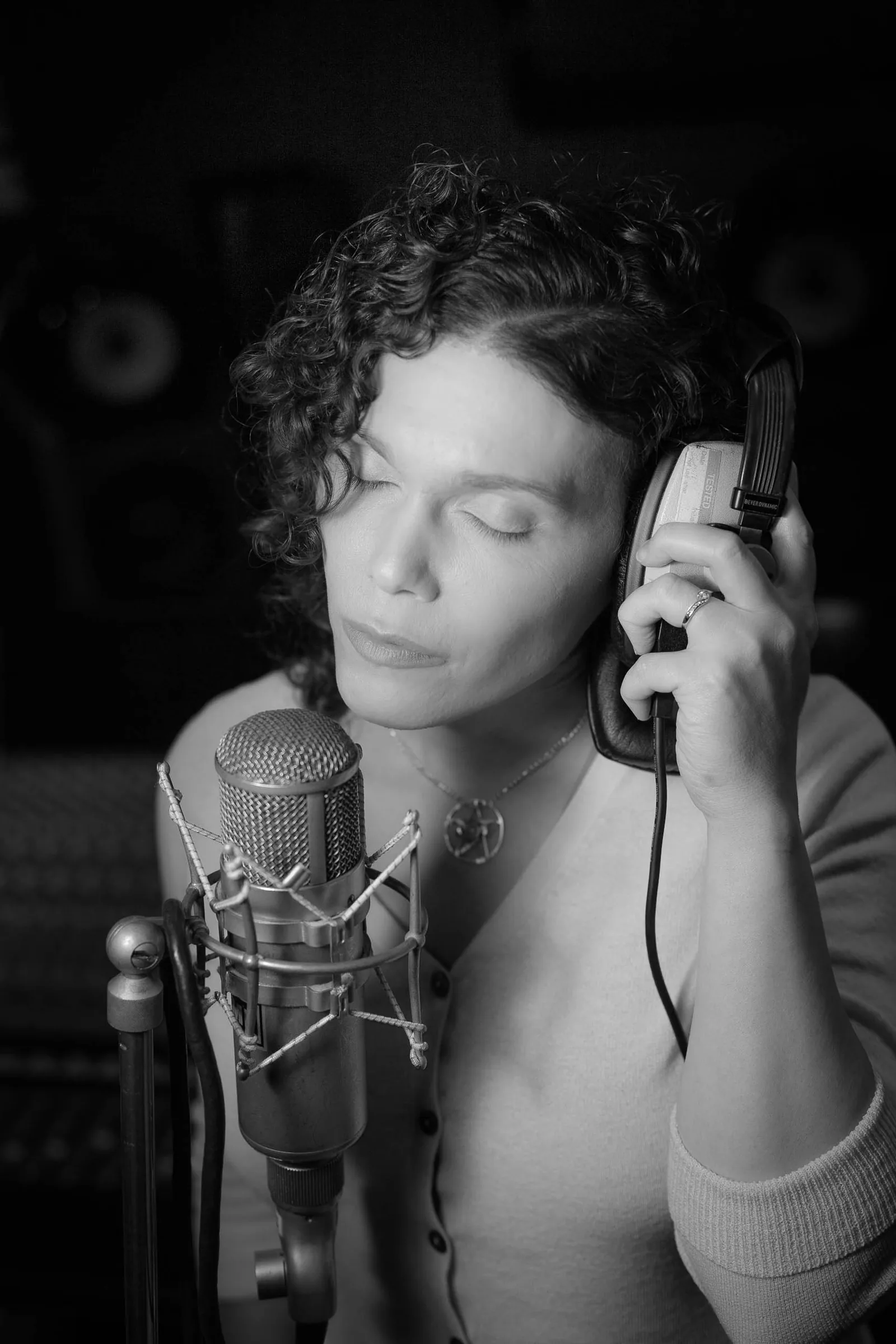Singer wearing headphones in front of a studio microphone Singer wearing headphones in front of a studio microphone