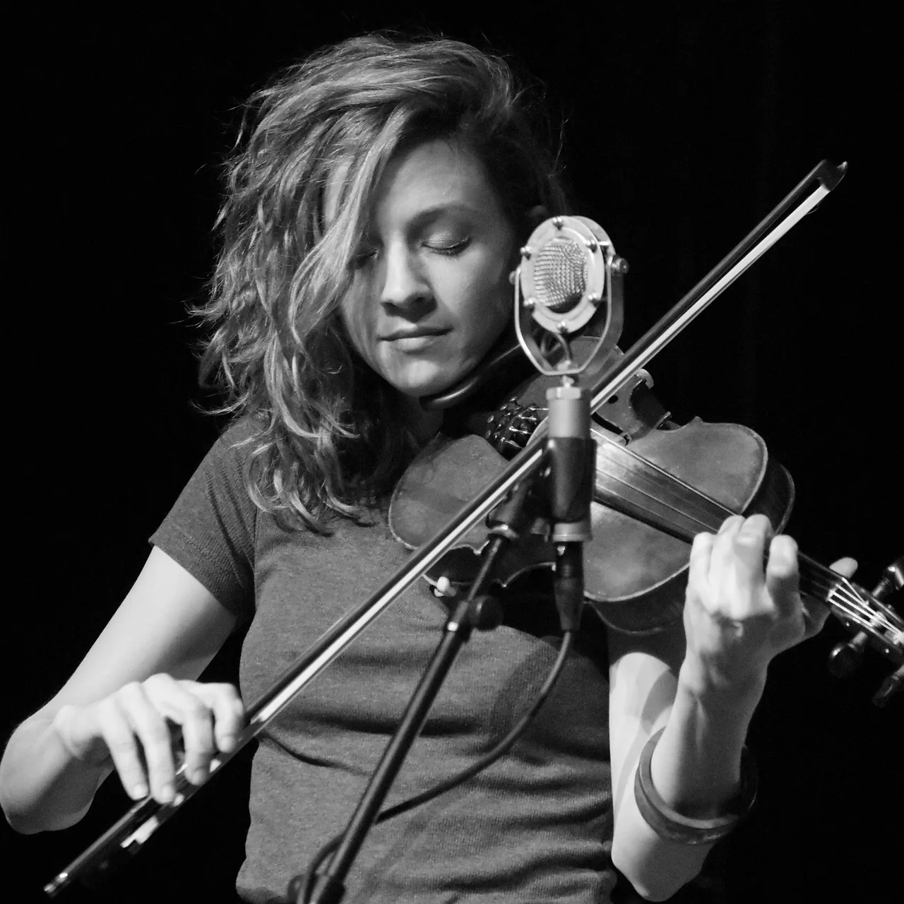 Violinist performing at a microphone onstage Violinist performing at a microphone onstage