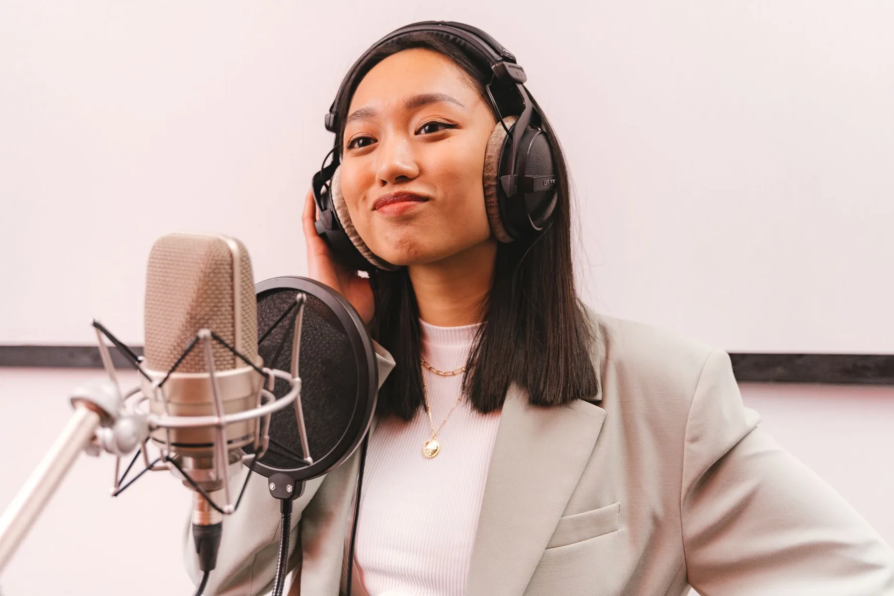 Singer wearing headphones in front of a studio microphone Singer wearing headphones in front of a studio microphone
