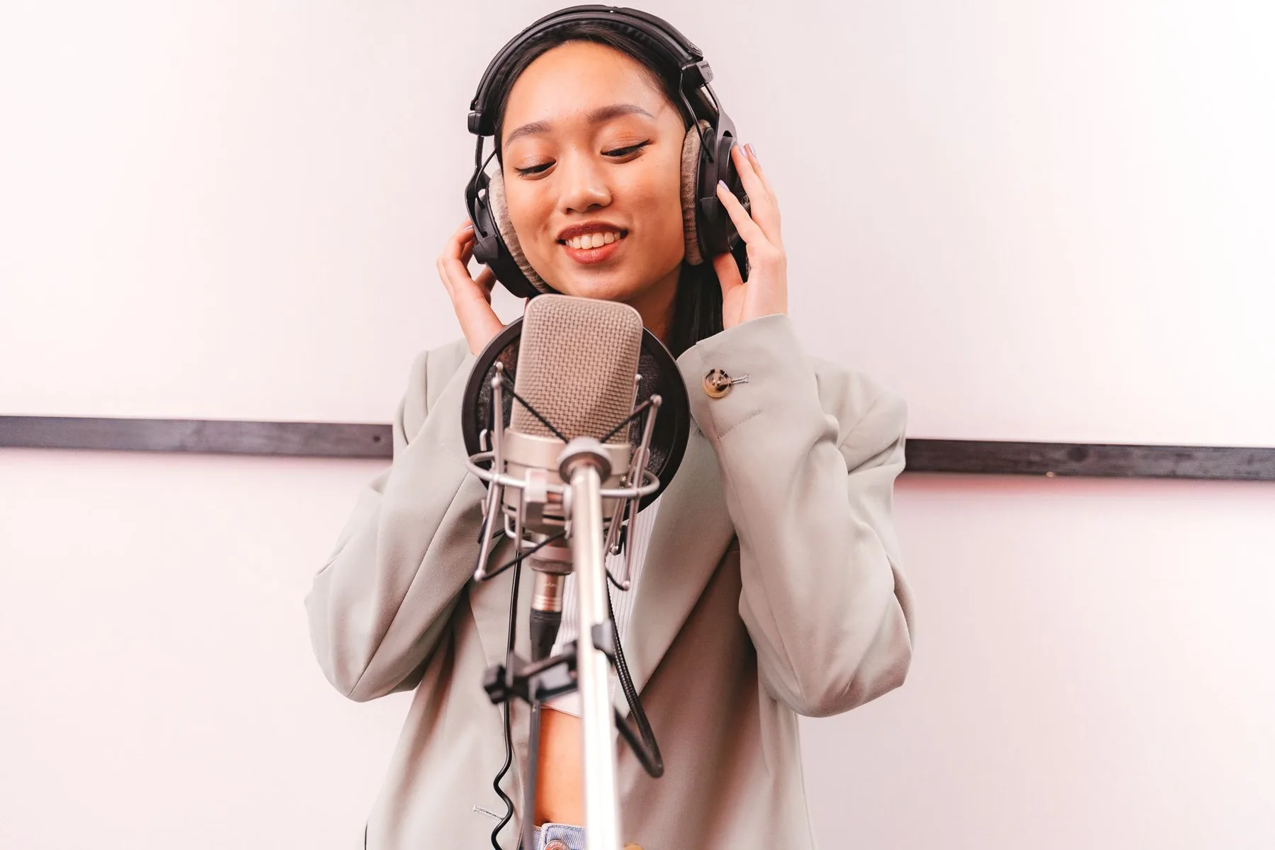 Singer wearing headphones in front of a studio microphone Singer wearing headphones in front of a studio microphone