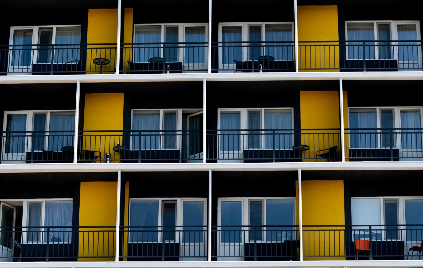 Apartment building balconies with yellow partitions and black railings Apartment building balconies with yellow partitions and black railings