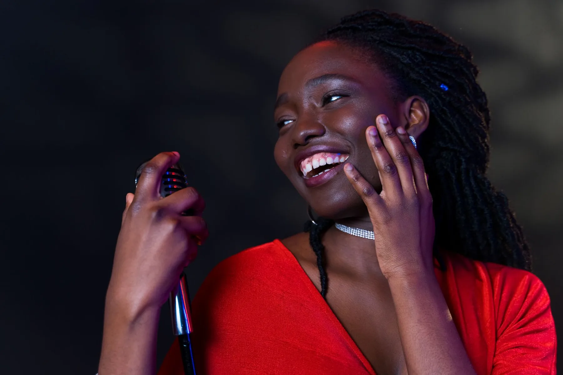 Smiling singer in a red dress at a microphone Smiling singer in a red dress at a microphone