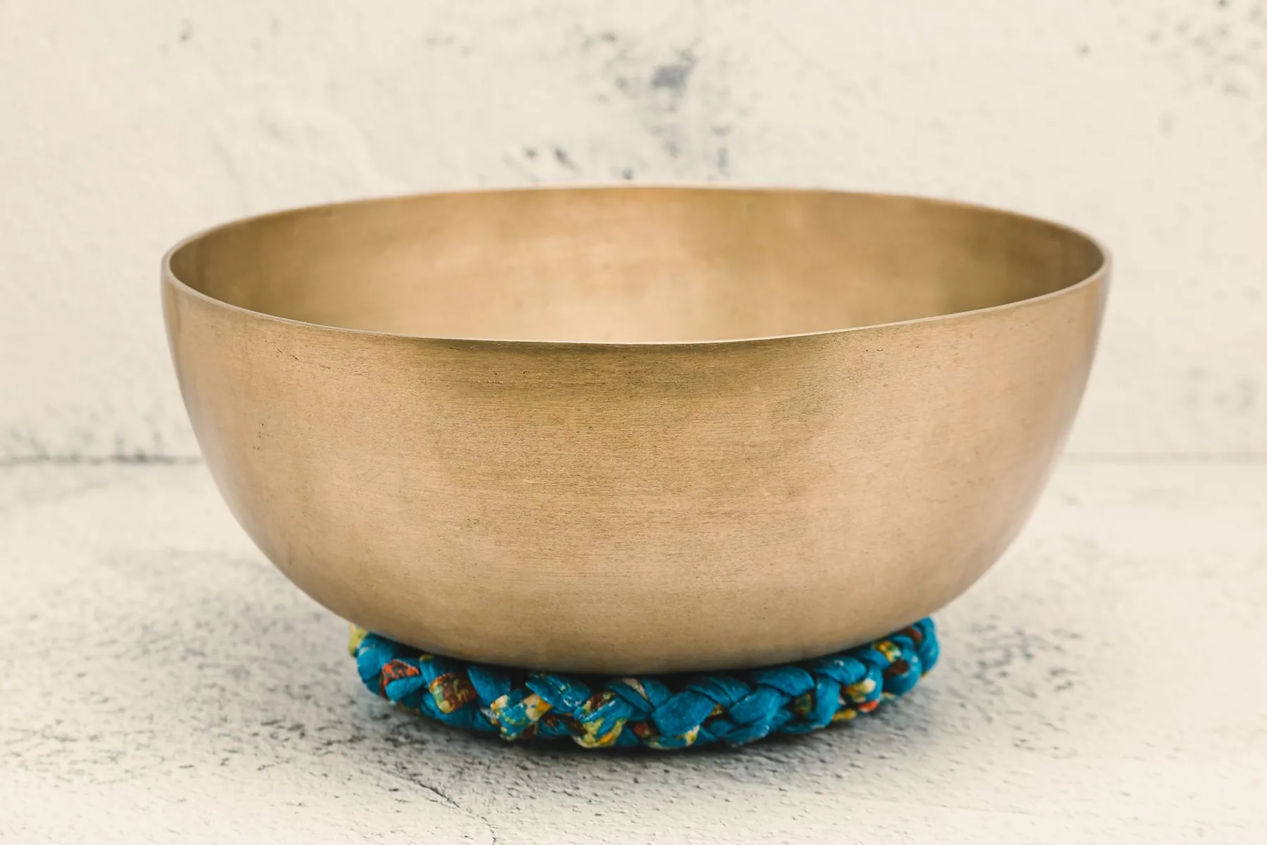 Golden Tibetan singing bowl on a blue woven cushion Golden Tibetan singing bowl on a blue woven cushion