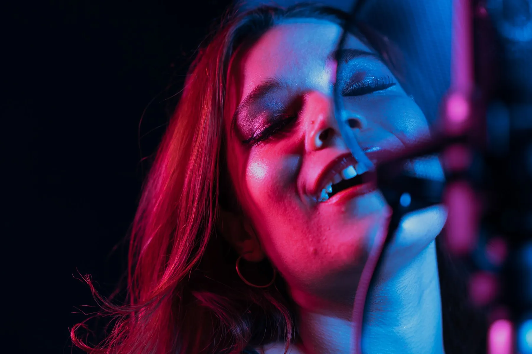 Singer at a microphone under pink and blue lights Singer at a microphone under pink and blue lights