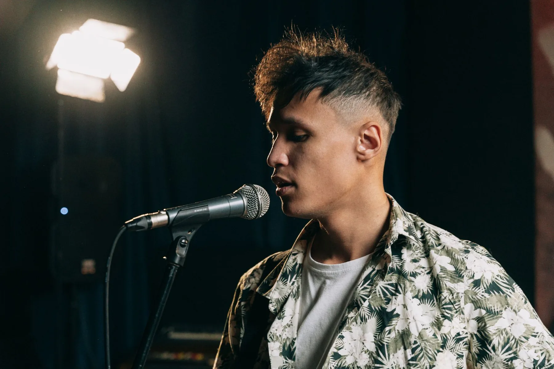 Singer in front of a microphone under a spotlight Singer in front of a microphone under a spotlight
