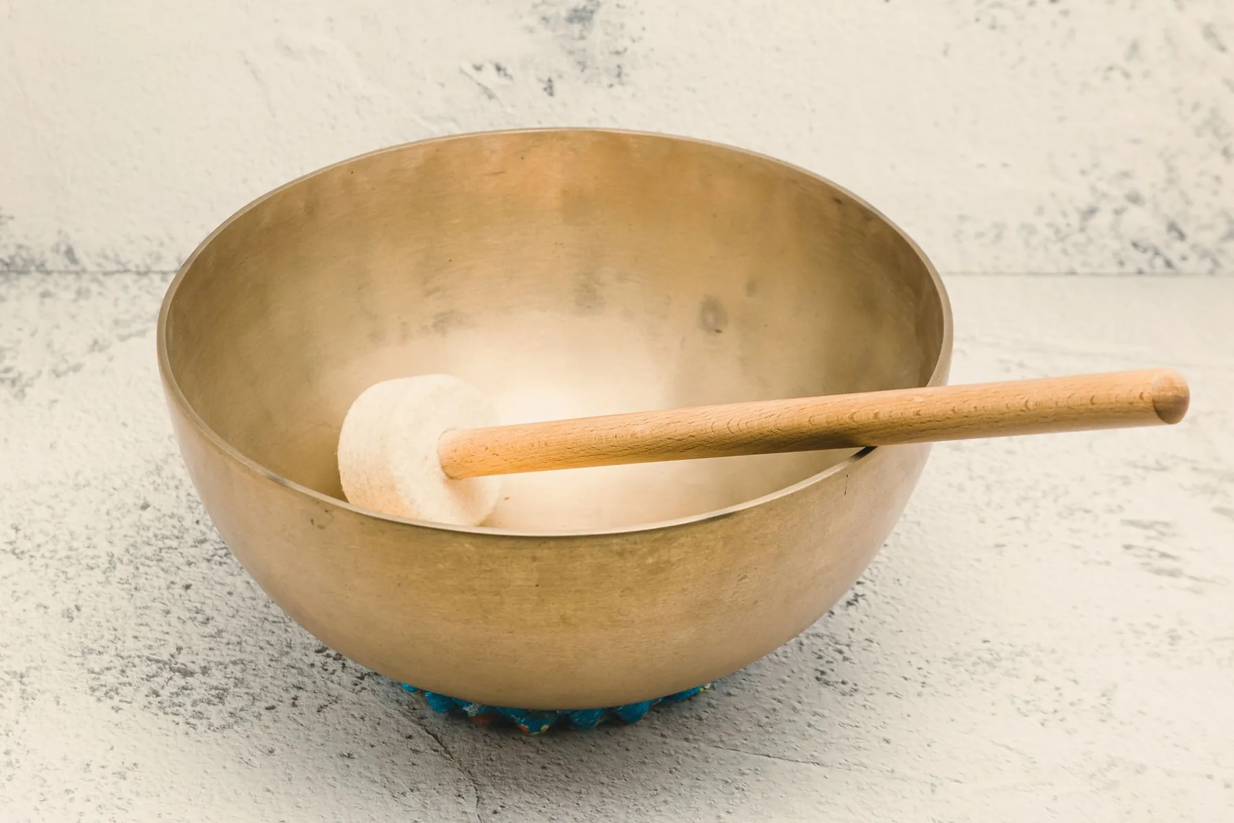 Tibetan singing bowl with a mallet on a blue cushion Tibetan singing bowl with a mallet on a blue cushion