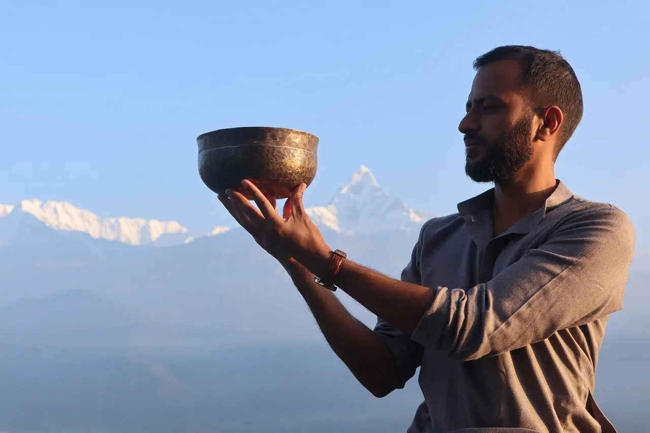 Man holding a Tibetan singing bowl in front of the mountains Man holding a Tibetan singing bowl in front of the mountains