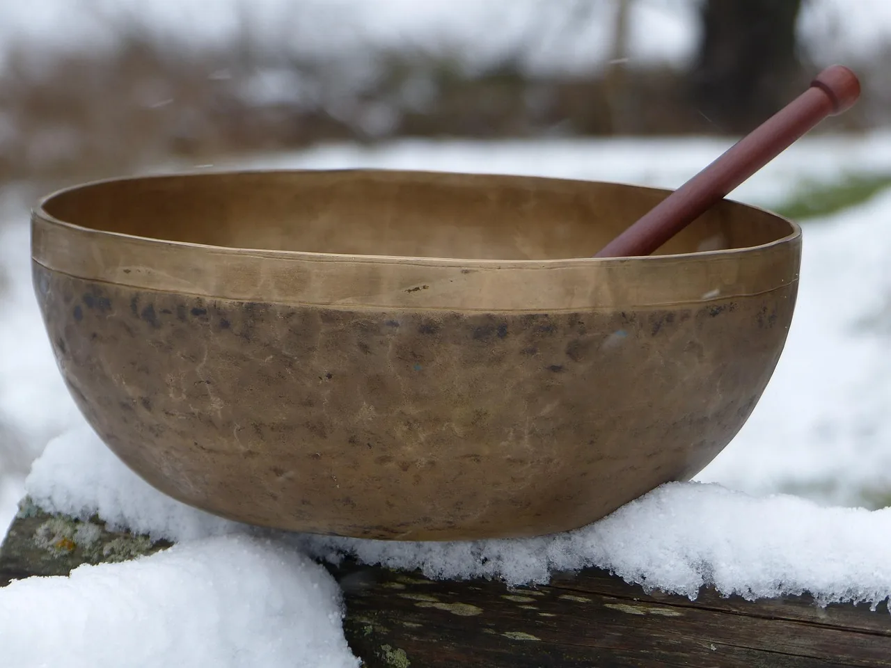 Tibetan singing bowl with a mallet in the snow Tibetan singing bowl with a mallet in the snow