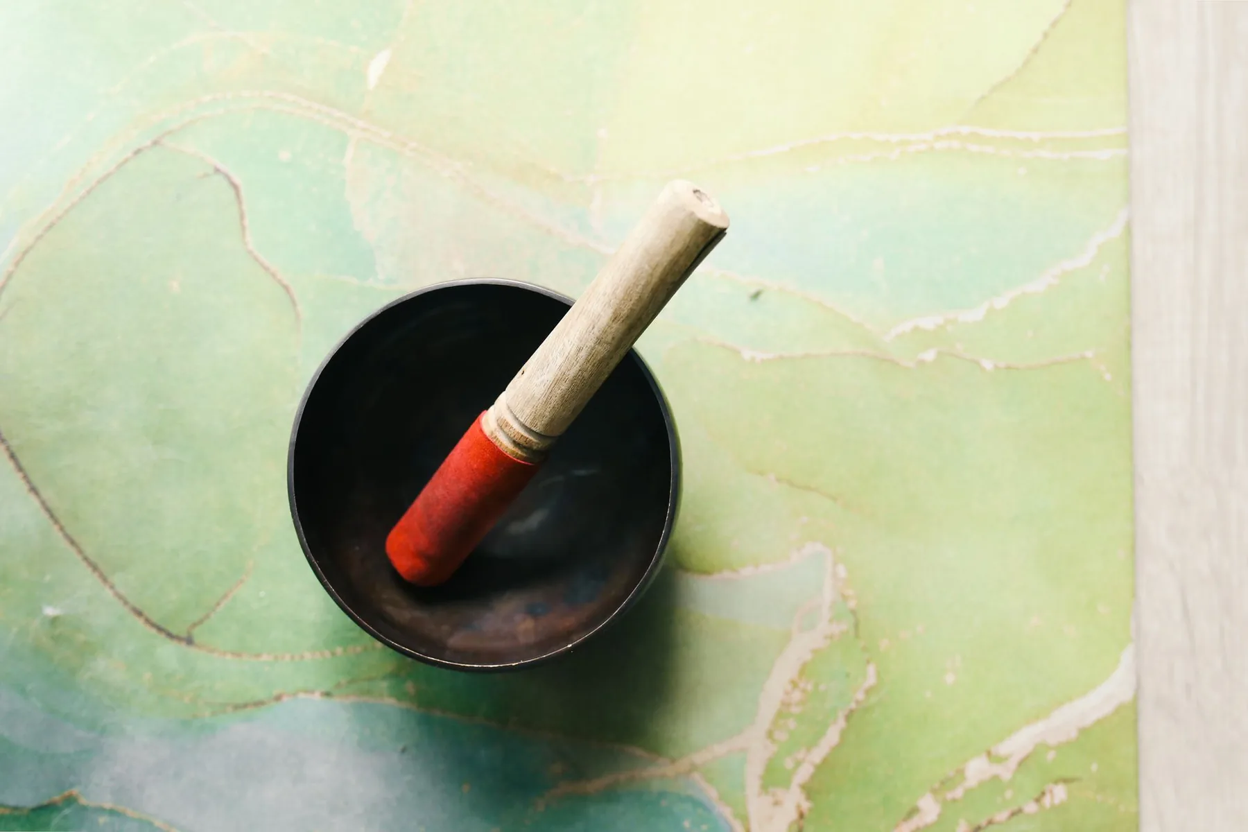 Tibetan singing bowl and mallet on a green surface Tibetan singing bowl and mallet on a green surface
