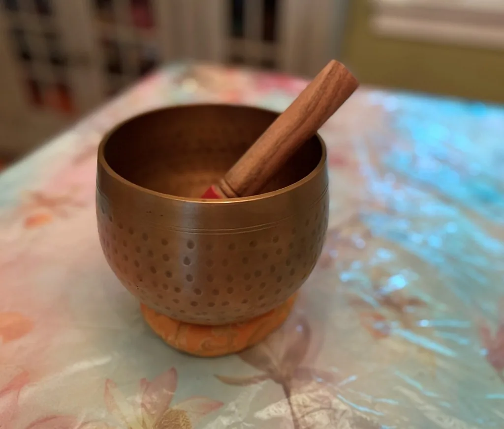 Tibetan singing bowl on an orange cushion with a mallet Tibetan singing bowl on an orange cushion with a mallet